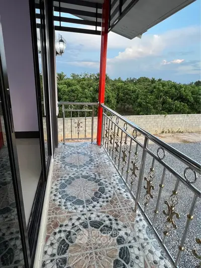 Charming balcony with ornate railing and scenic view of lush greenery, perfect for relaxation.