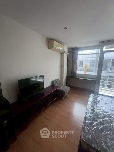 Cozy bedroom with natural light and modern furnishings in urban apartment.