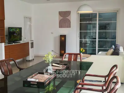 Spacious living room with modern decor and glass dining table, perfect for entertaining.