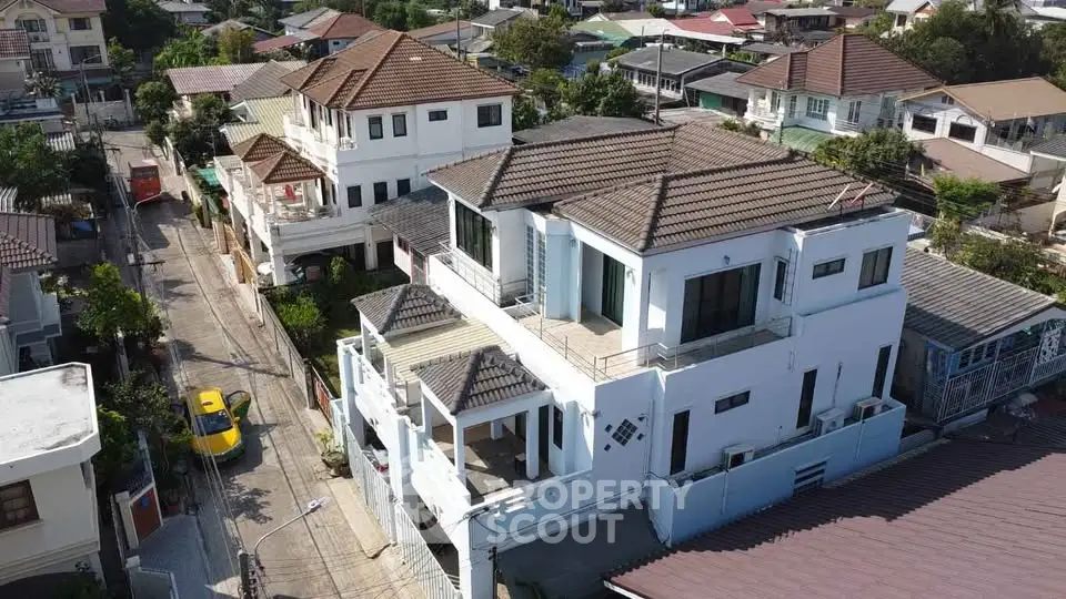 Stunning aerial view of a spacious multi-story house with a tiled roof in a serene neighborhood.