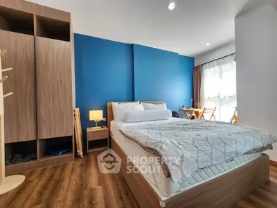 Modern bedroom with wooden flooring and blue accent wall, featuring cozy bed and ample storage space.