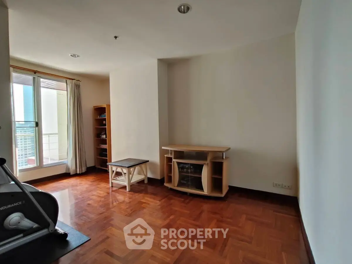 Spacious room with wooden flooring and balcony access in modern apartment