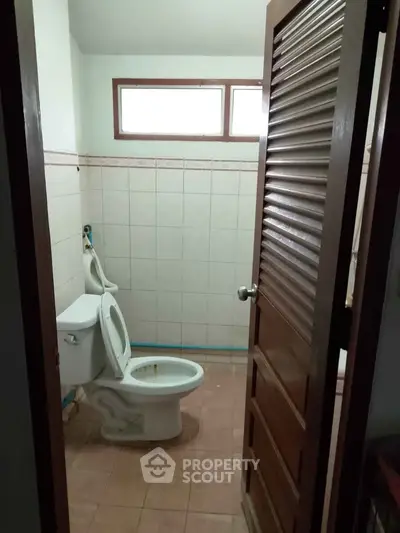 Cozy bathroom with tiled walls and wooden door, featuring a standard toilet.