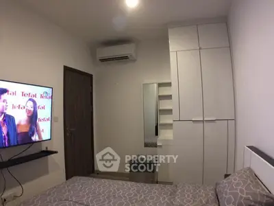 Cozy bedroom with modern decor and wall-mounted TV in a stylish apartment.