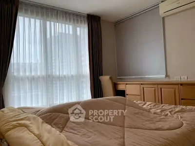 Cozy bedroom with large window and modern furnishings in a stylish apartment.