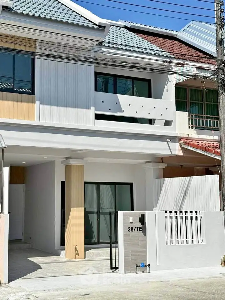 Modern townhouse exterior with sleek design and gated entrance in a sunny neighborhood.