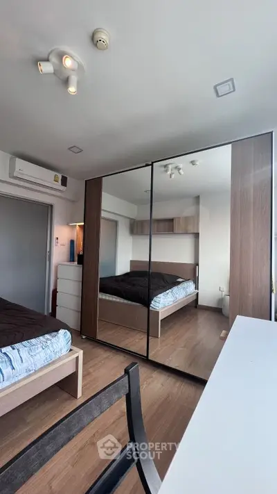 Modern bedroom with mirrored wardrobe and wooden flooring