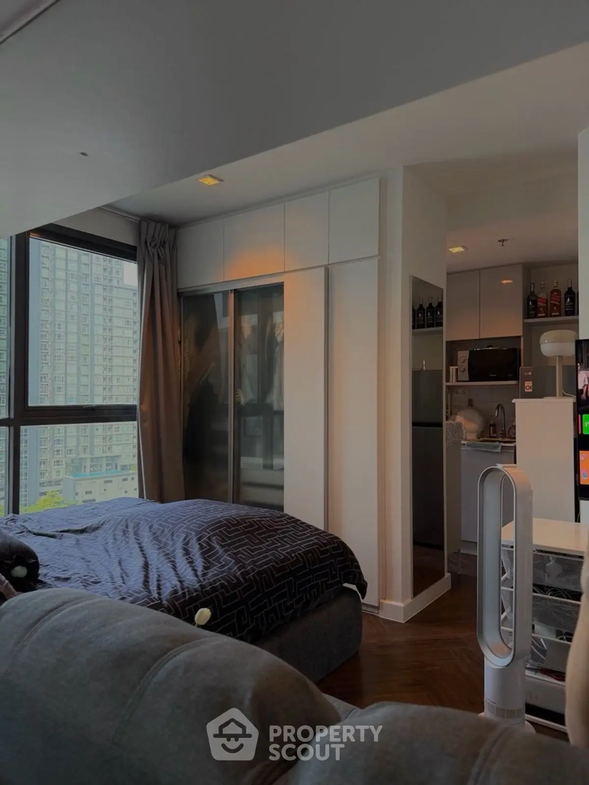 Modern studio apartment with cozy bedroom and compact kitchen, featuring large windows and city view.