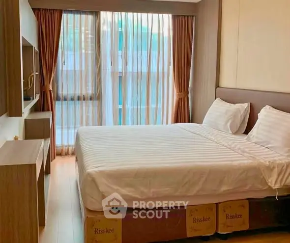 Modern bedroom with large window and elegant furnishings in a stylish apartment.