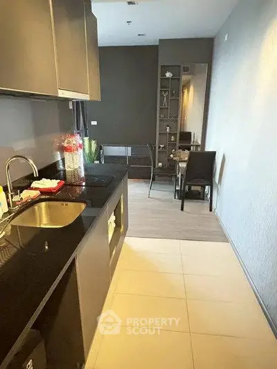 Modern kitchen with sleek black countertops and dining area in open layout apartment.