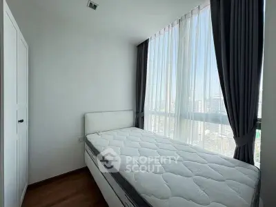 Bright bedroom with large windows and city view, featuring a comfortable bed and modern decor.