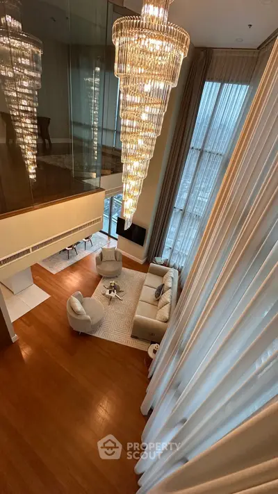 Luxurious high-ceiling living room with elegant chandelier and floor-to-ceiling windows.