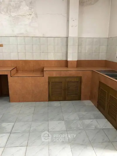 Spacious kitchen with tiled walls and wooden cabinets, ideal for renovation.