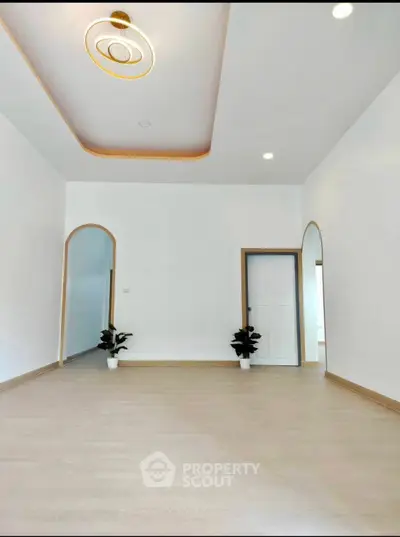 Spacious modern living room with elegant ceiling design and wooden flooring.