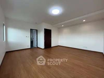 Spacious empty room with wooden flooring and modern lighting, ideal for customization.