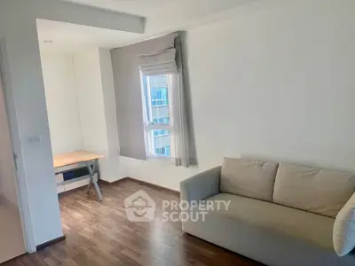 Modern living room with cozy sofa and wooden flooring, bright natural light through window.