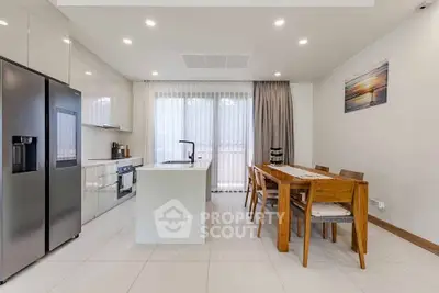 Modern kitchen with sleek appliances and dining area, featuring a stylish open layout and elegant decor.