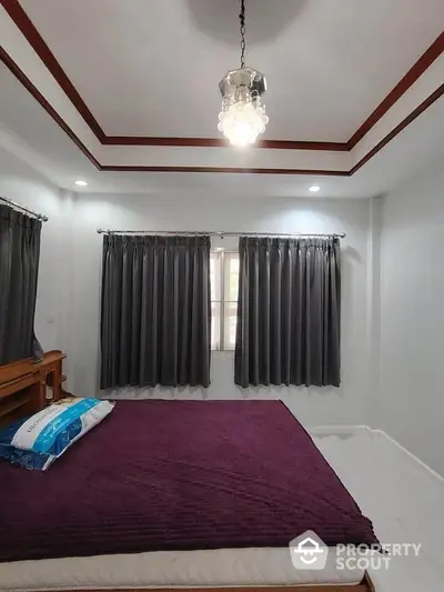 Spacious bedroom with elegant ceiling design and large windows for natural light.