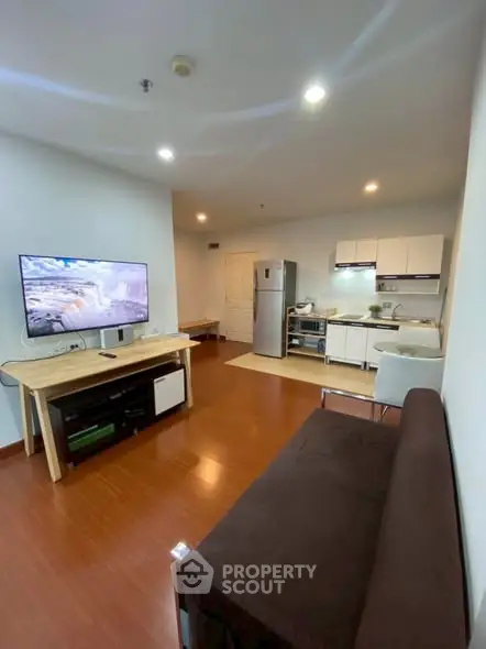 Modern open-layout living room with kitchen, featuring sleek furniture and appliances.