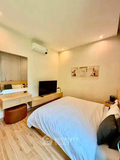 Modern bedroom with stylish decor and wooden flooring, featuring a mounted TV and air conditioning.