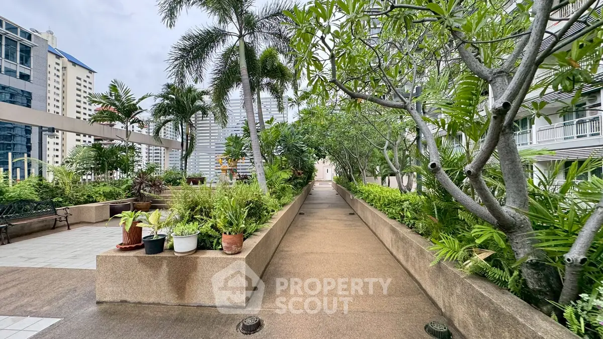 Lush garden pathway in modern residential complex with city views