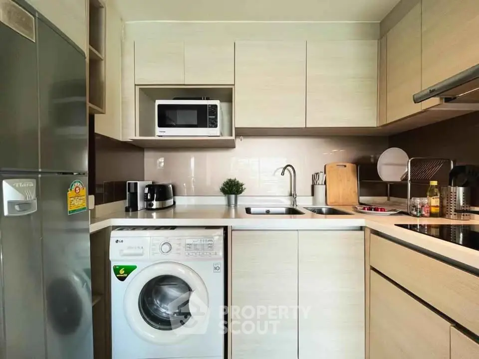 Modern kitchen with washing machine and microwave in sleek cabinetry