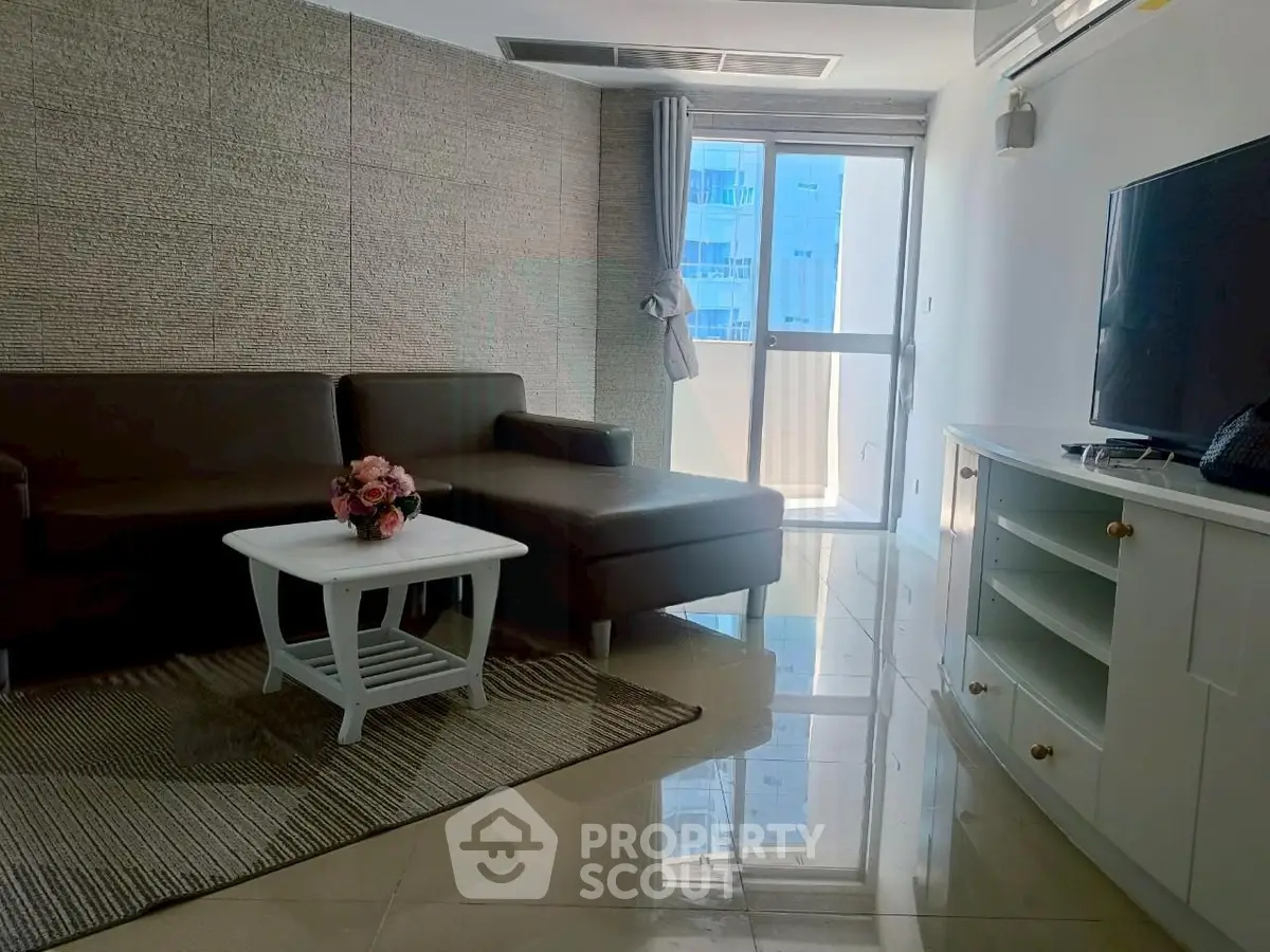 Modern living room with sleek furniture and large window offering natural light.