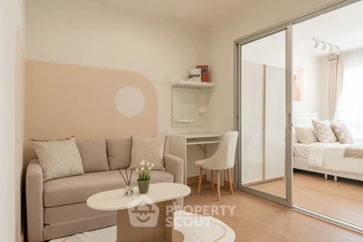 Modern living room with cozy sofa and study area, adjacent to a bright bedroom.