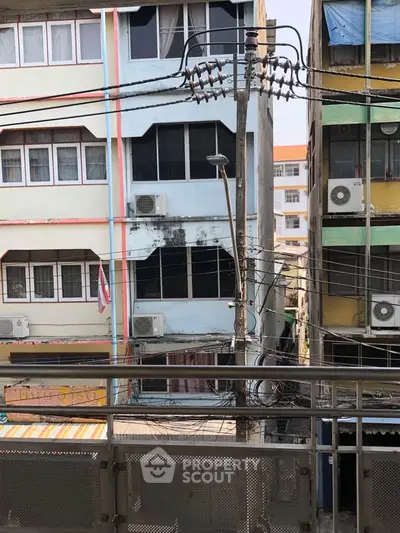 Urban residential buildings with air conditioning units and electrical wires in a bustling city area.