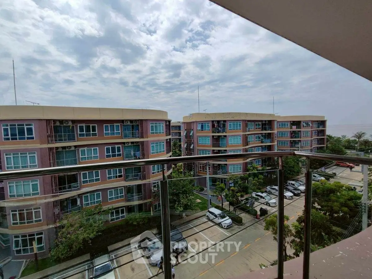 Scenic view from balcony overlooking modern apartment complex and parking area.