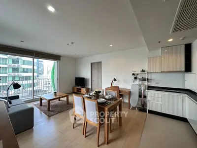 Modern open-plan living room and kitchen with city view, stylish furniture, and natural light.