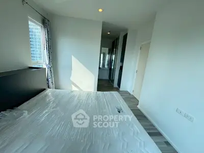 Modern bedroom with large window and sleek flooring in a high-rise apartment.