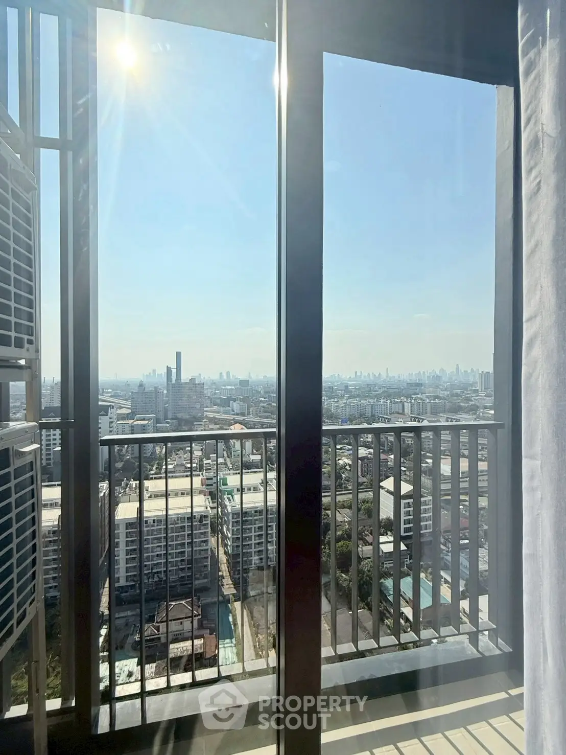 Stunning high-rise balcony view with expansive cityscape and clear blue sky.