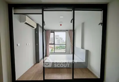 Modern bedroom with large windows and city view, featuring sleek design and ample natural light.
