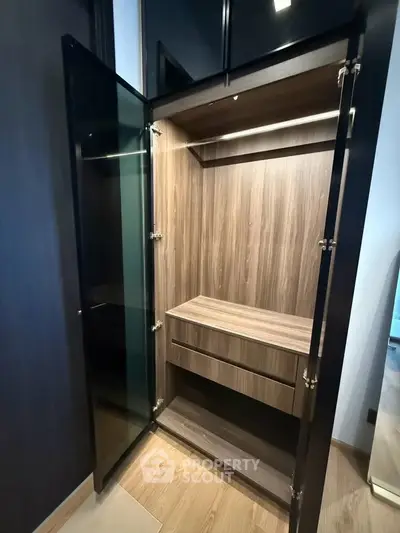 Modern wooden walk-in closet with glass doors and built-in lighting