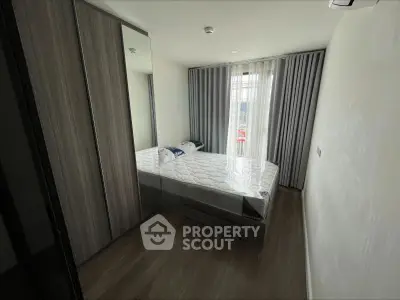 Modern bedroom with sleek wooden flooring and large mirrored wardrobe