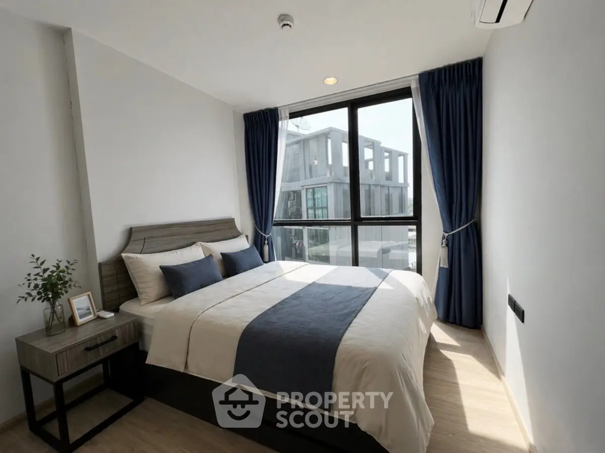Modern bedroom with large window and stylish decor in a contemporary apartment.