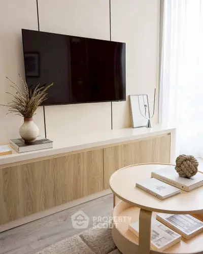 Modern living room with sleek TV setup and stylish decor, featuring a wooden cabinet and round coffee table.