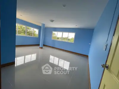 Spacious empty room with glossy tiled floors and large windows offering natural light.