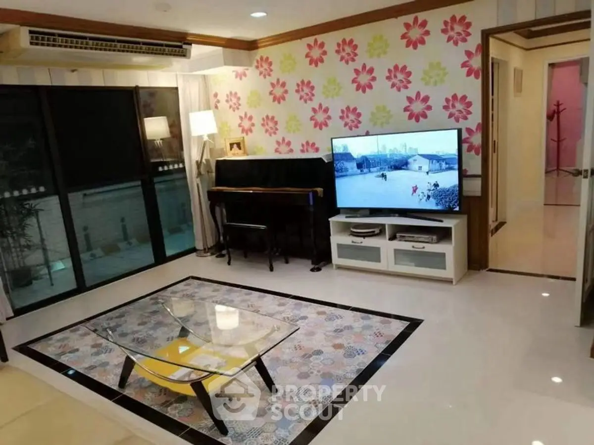 Charming living room with floral accent wall, modern furniture, and large TV, perfect for relaxation.