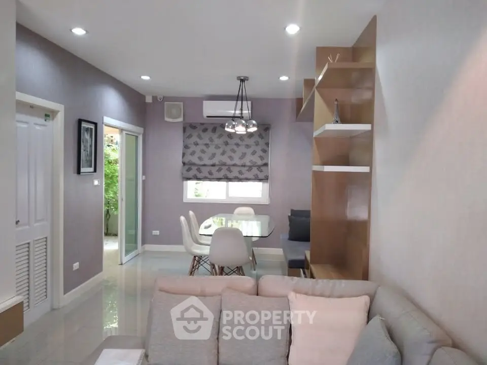 Modern living room with stylish decor and dining area, featuring elegant lighting and cozy seating.