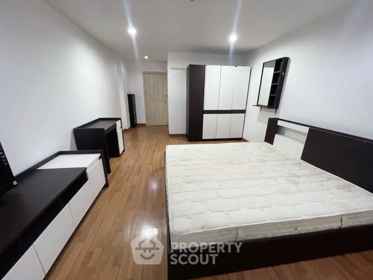 Spacious bedroom with modern furniture and wooden flooring, perfect for comfort and style.
