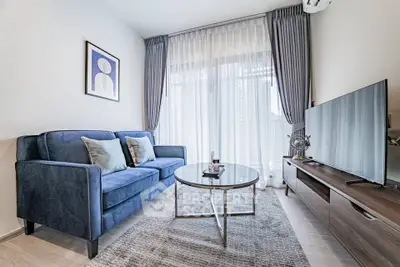 Modern living room with blue sofa, large TV, and elegant decor in a bright apartment.