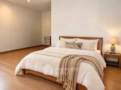 Spacious bedroom with cozy decor and wooden flooring