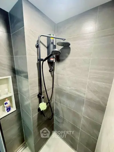 Modern bathroom with sleek shower fixtures and gray tiled walls.