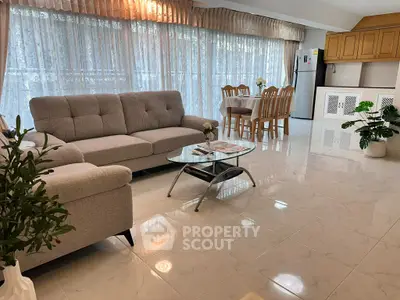 Spacious living room with elegant decor and natural light, featuring a cozy sofa and dining area.