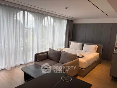 Luxurious bedroom with modern decor and large windows offering natural light and a serene view.