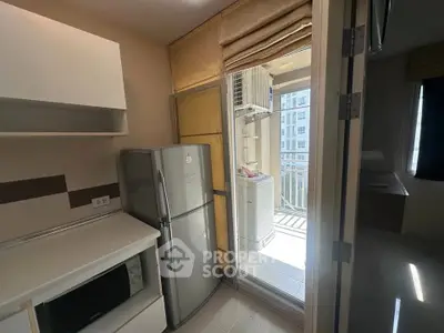 Modern kitchen with fridge and microwave leading to balcony with washing machine
