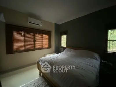 Cozy bedroom with large bed and window blinds, perfect for relaxation.