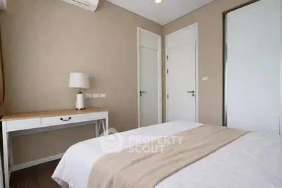 Cozy bedroom with neutral tones and elegant decor, featuring a stylish desk and comfortable bedding.